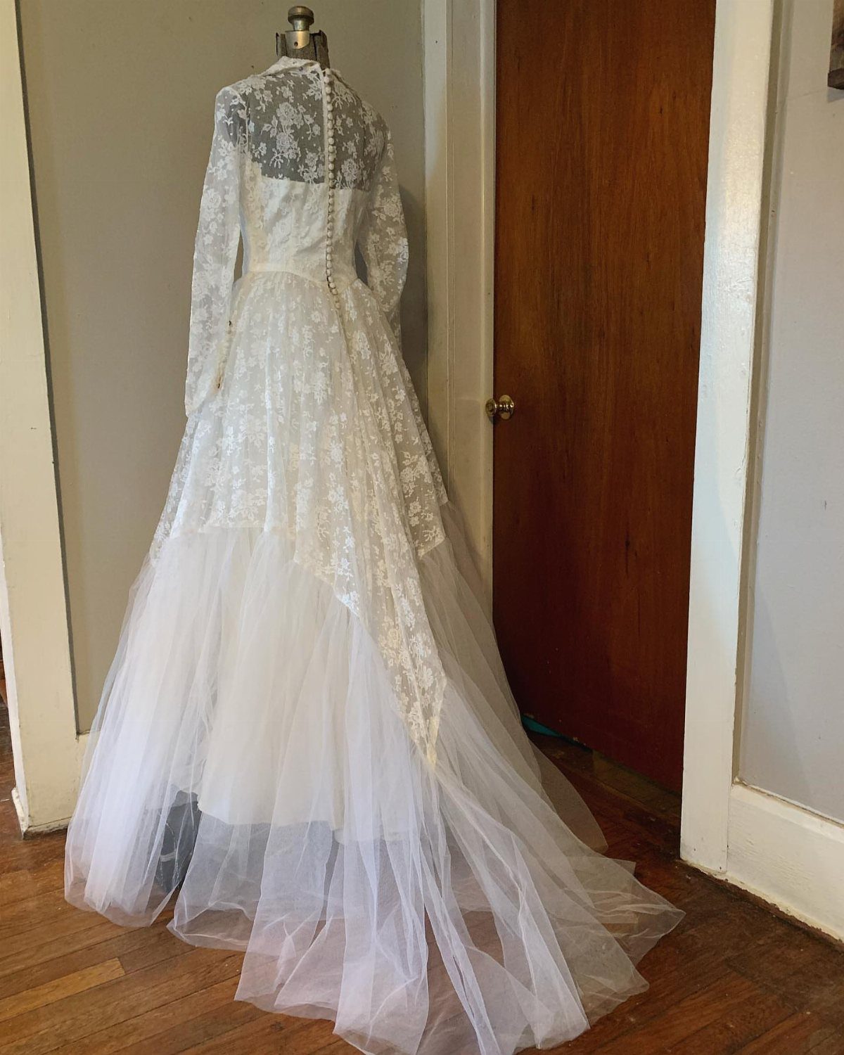 White vintage wedding dress with lace sleeves and floral lace detailing on a mannequin