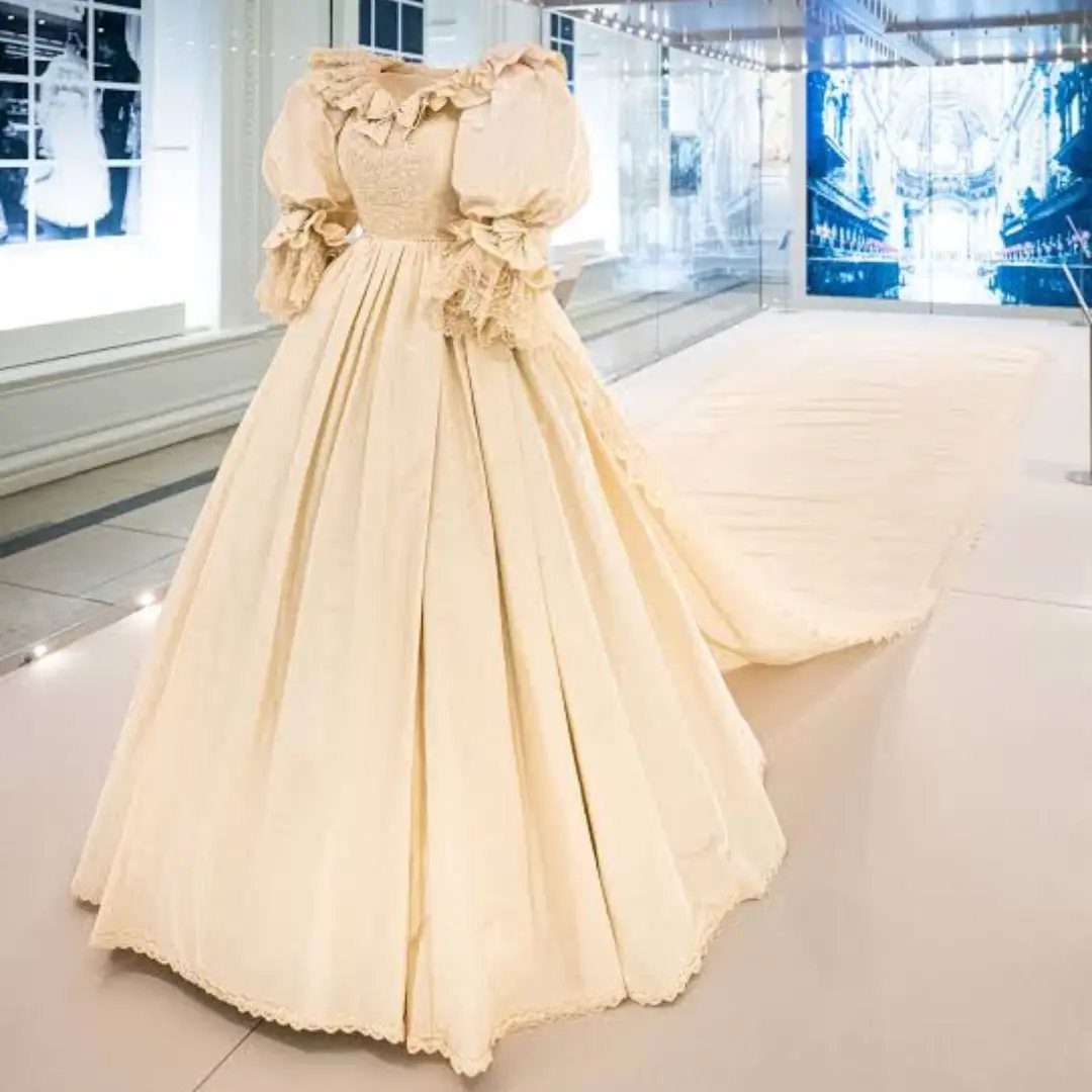 Cream vintage wedding gown with lace bodice and puffed sleeves on a mannequin.
