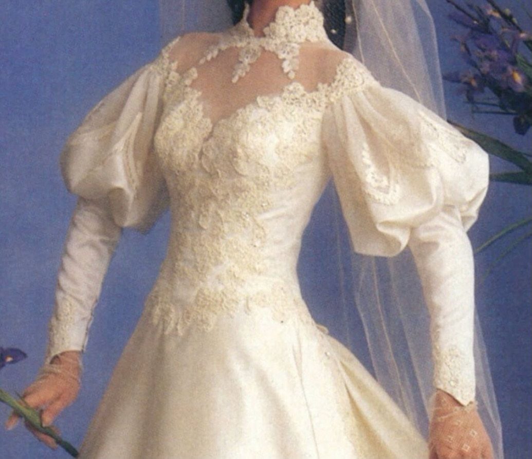 White satin wedding gown with lace bodice and large puffed sleeves and veil