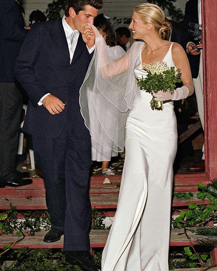 Bride in a minimalist white 1990s wedding dress and veil being kissed by groom.