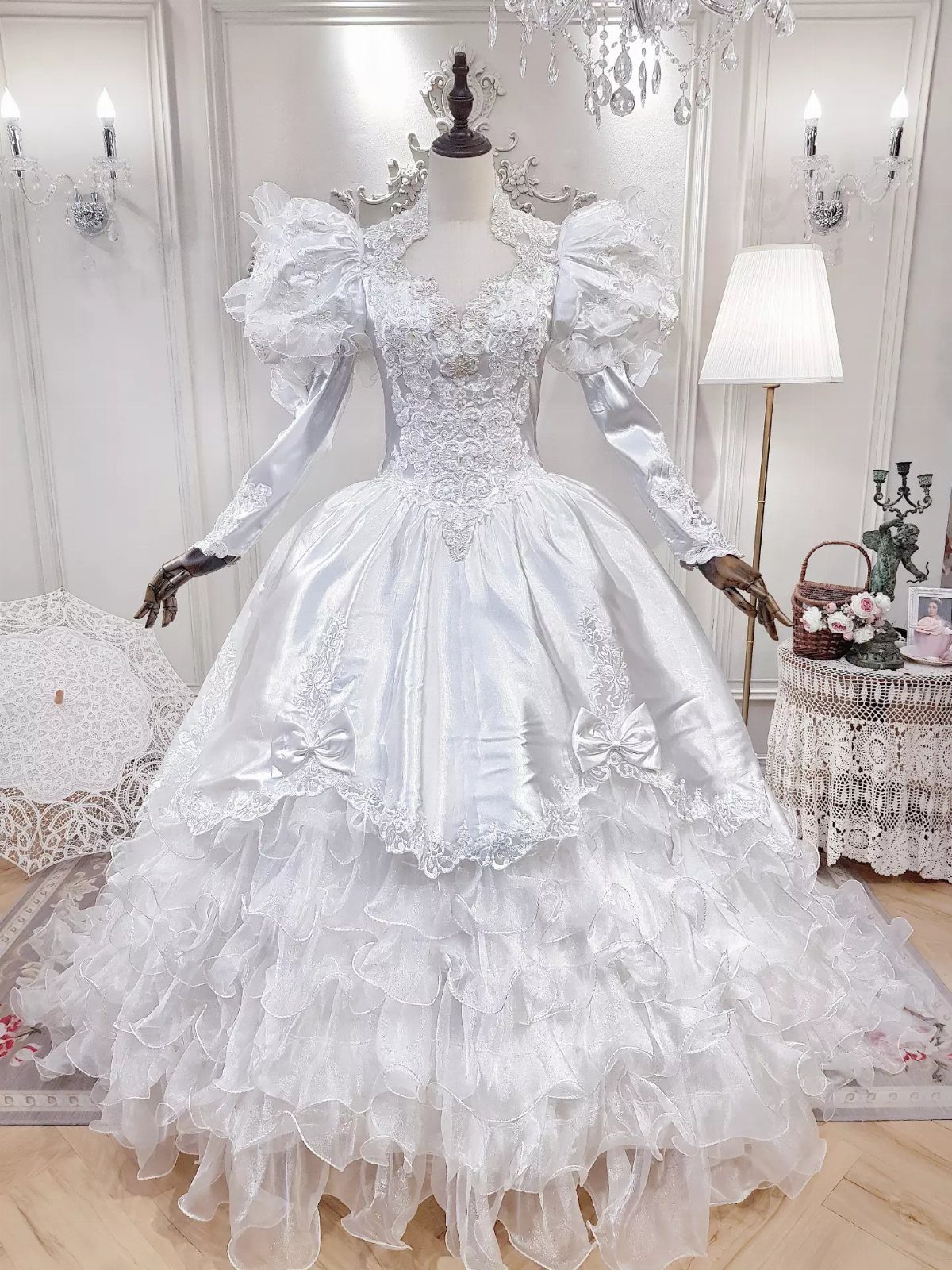 Ornate white satin wedding dress with puffed sleeves and ruffled skirt on mannequin