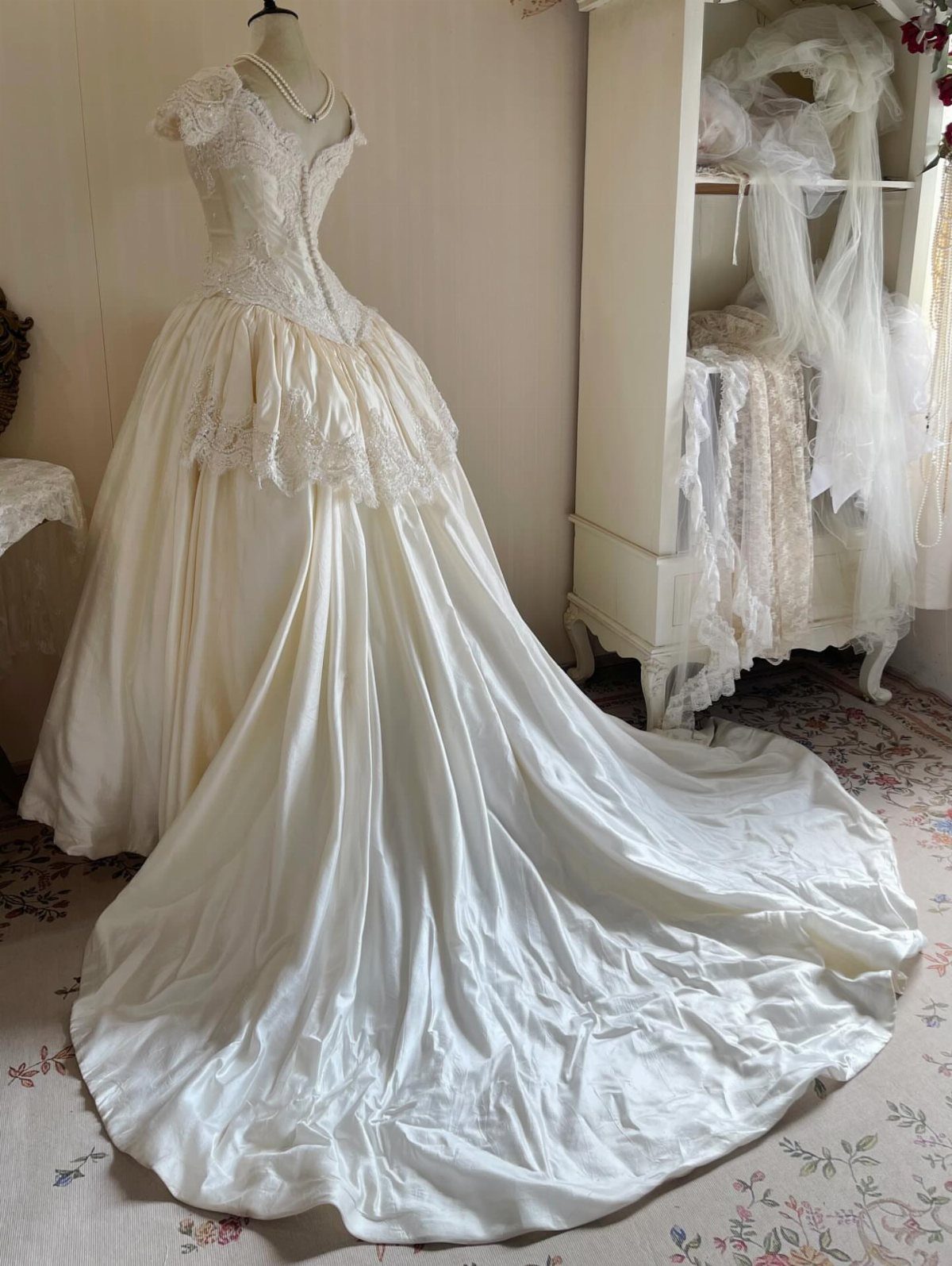 Vintage white wedding dress with lace bodice and full satin skirt on mannequin