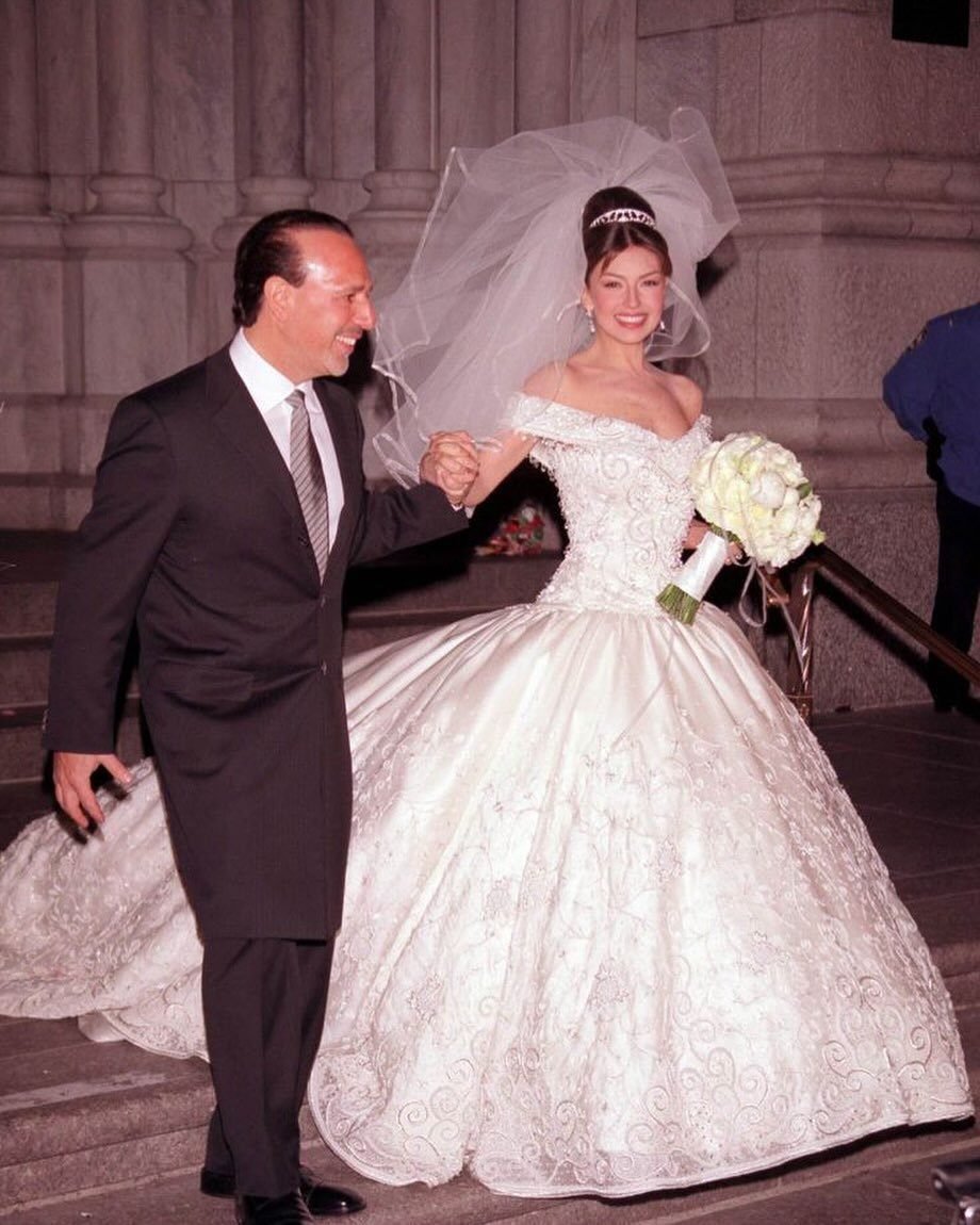 Bride in a voluminous white embroidered wedding gown walking with a man in suit.