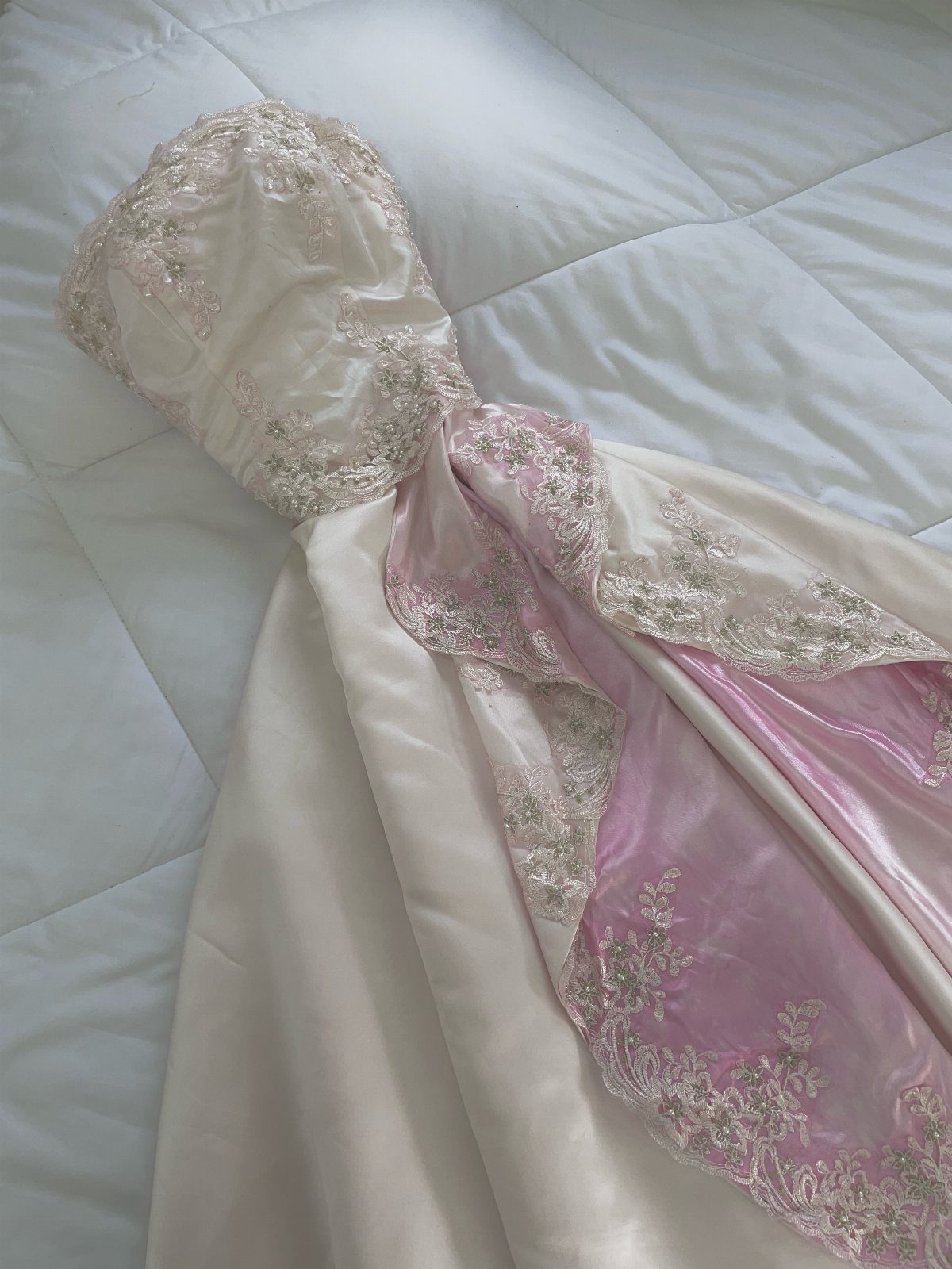 Strapless white wedding gown with embellished bodice and pink satin lace underskirt.