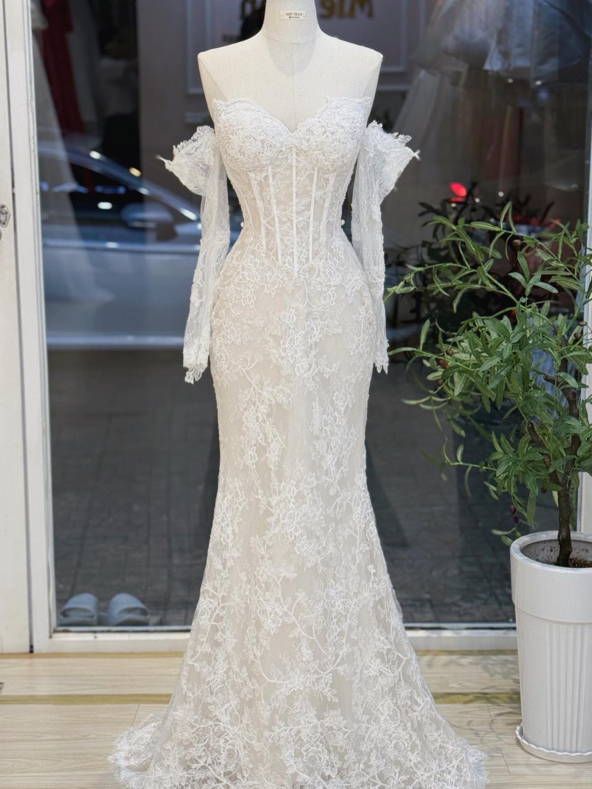 White lace wedding dress with corset bodice and detached sleeves on a mannequin
