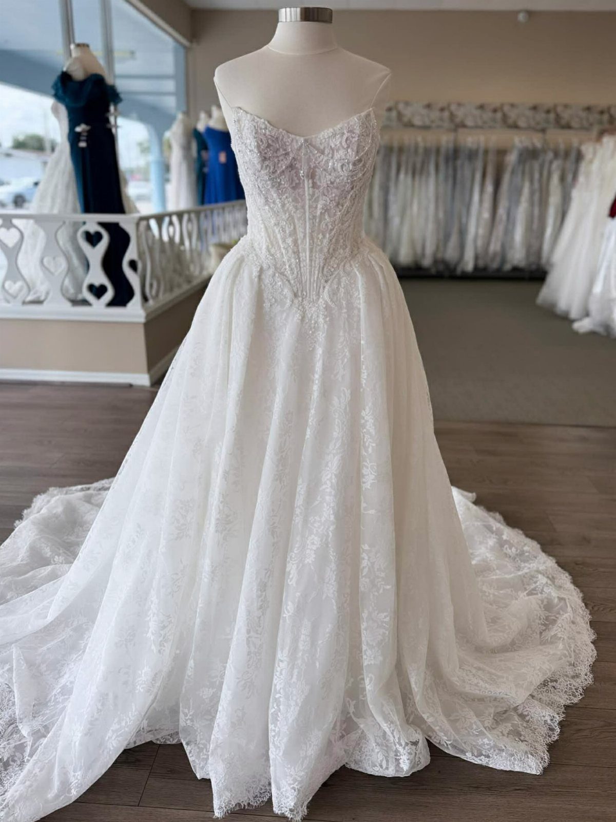 White lace wedding gown with a full skirt on a bridal mannequin.