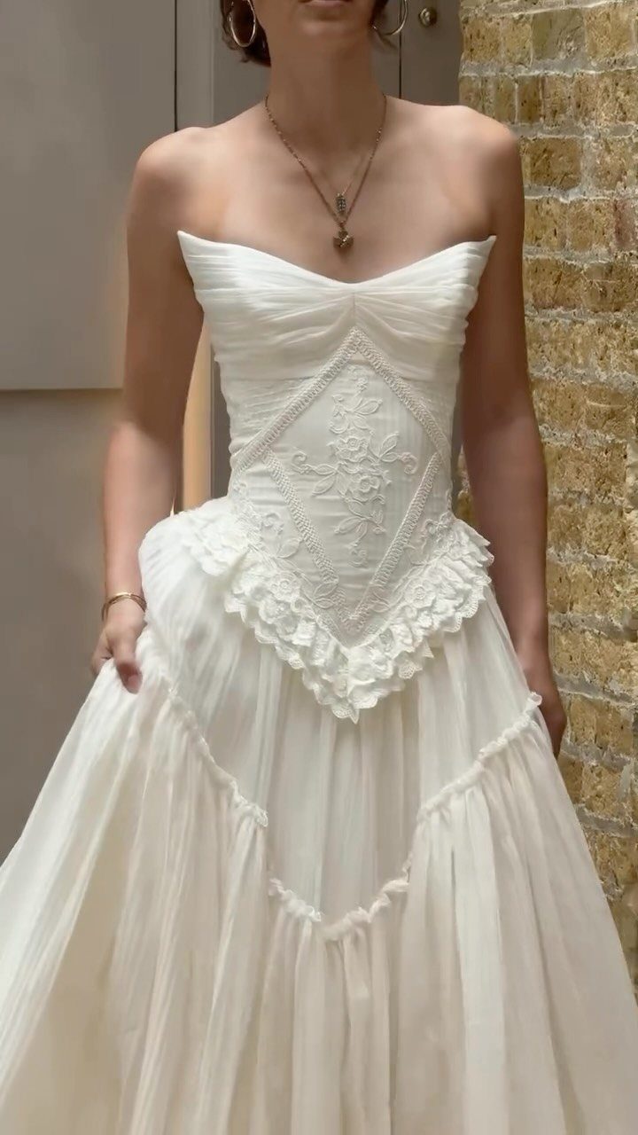 Woman wearing a strapless white A-line wedding gown with lace bodice and tiered skirt