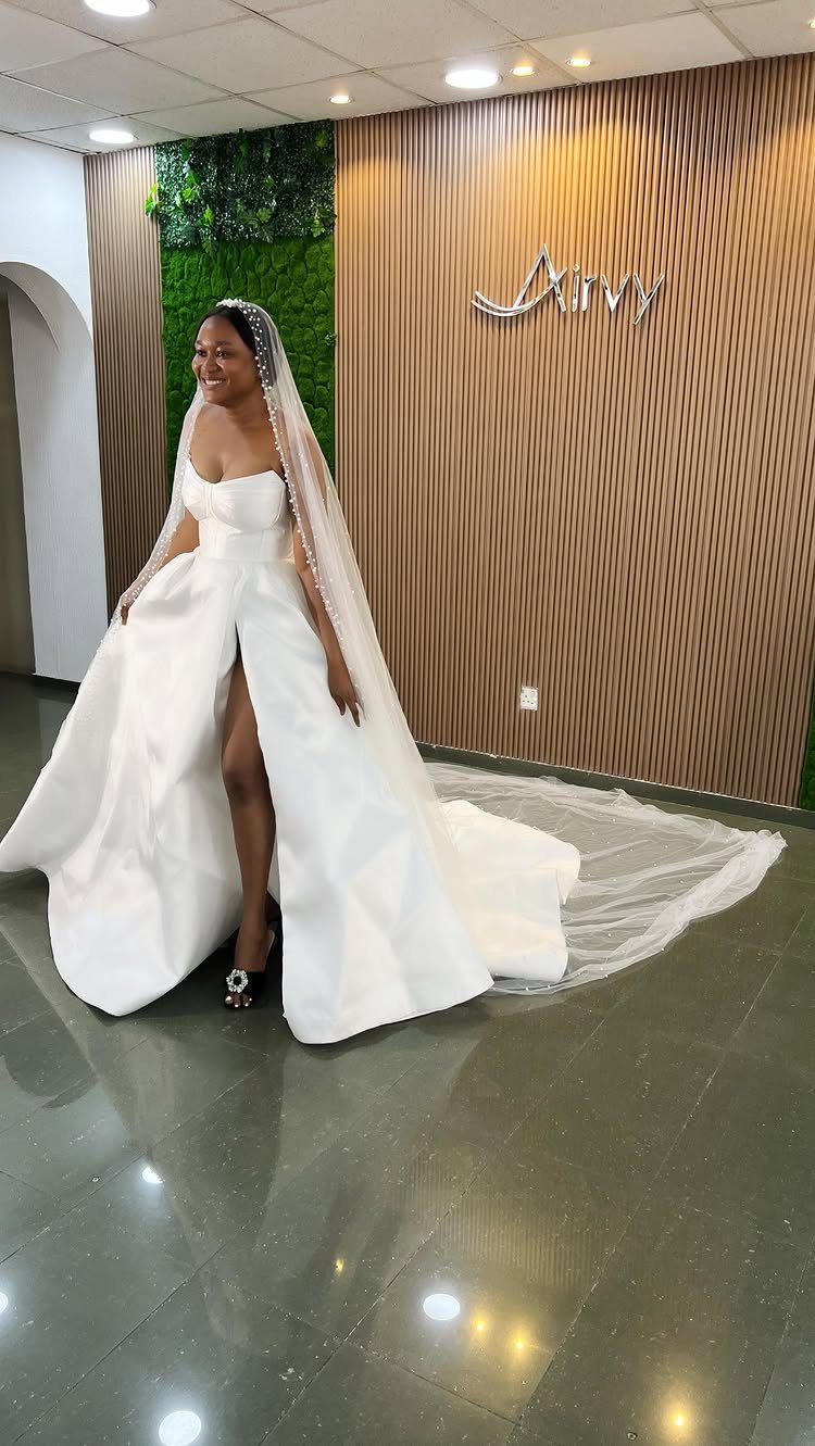 Woman in a minimalist white A-line wedding gown with a long veil and slit.