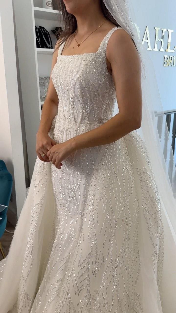 Woman wearing a sparkling white A-line wedding gown and a long white veil.