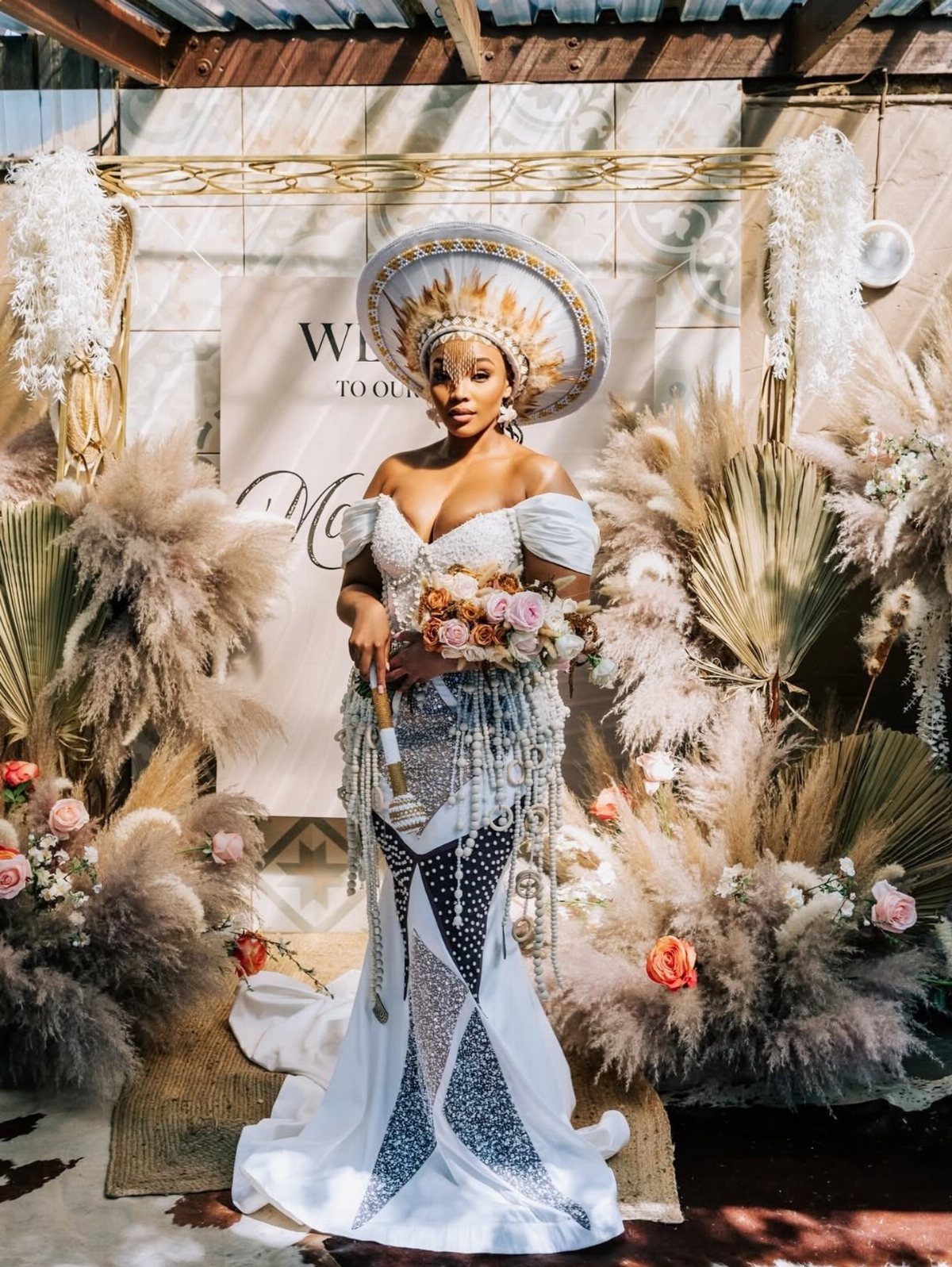 Woman in a white and blue patterned bridal gown with a large headpiece.