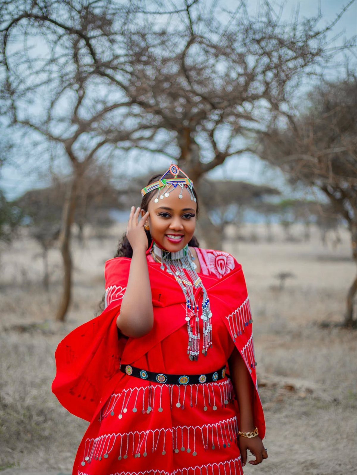 Woman in a red Maasai wedding dress with traditional beaded jewelry and headpiece.