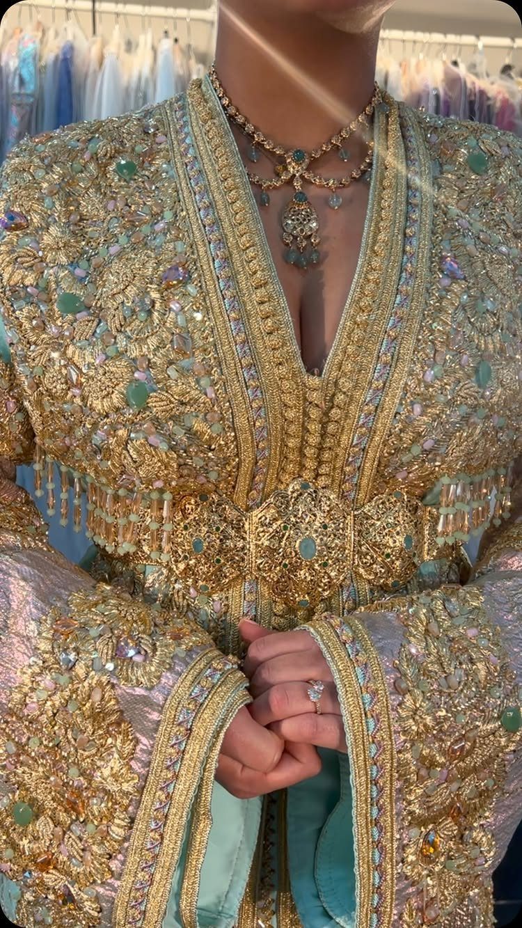Intricately embroidered gold Moroccan caftan with a matching belt and gold necklace.