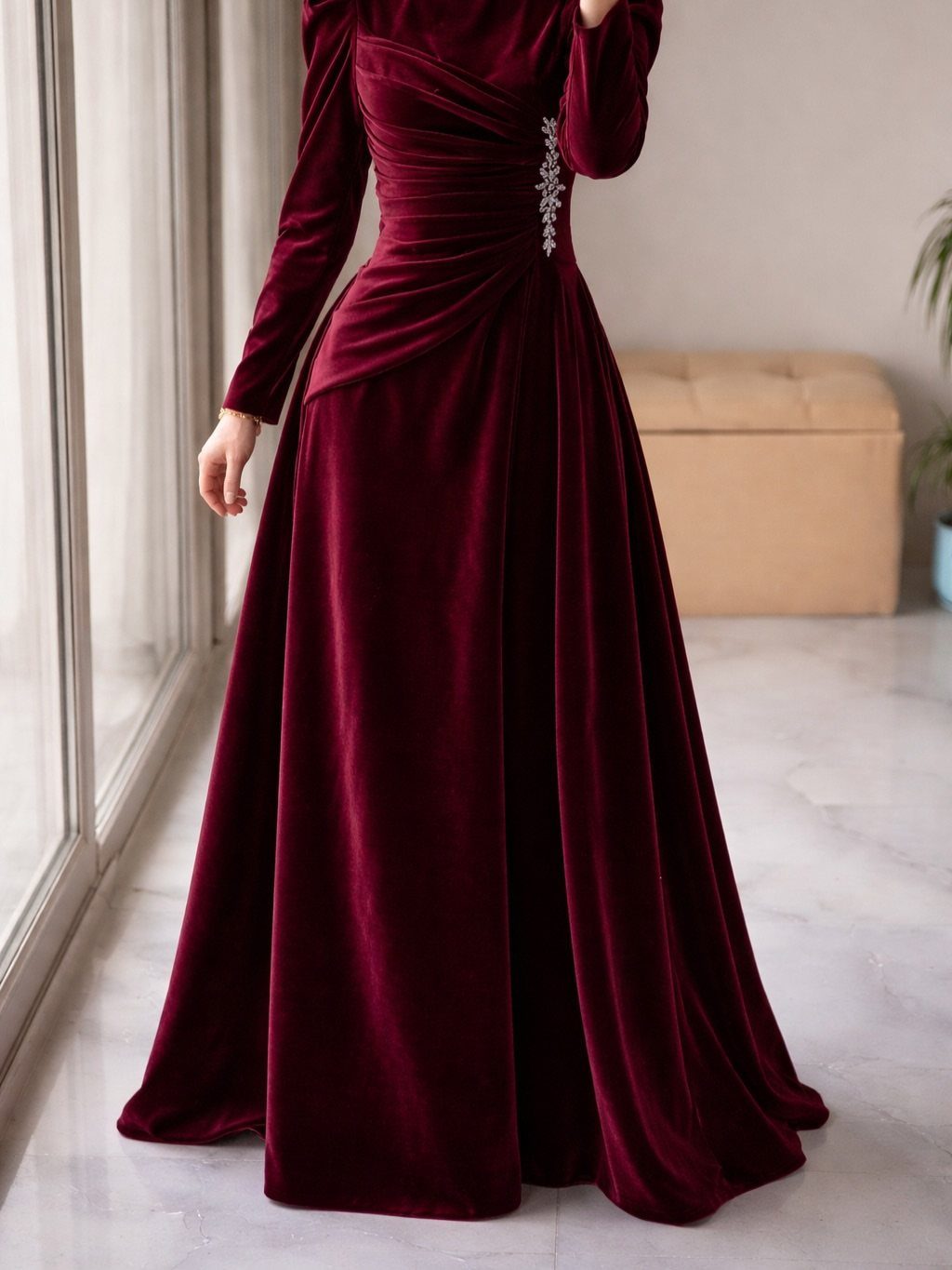 Burgundy velvet floor-length dress with long sleeves and a sparkling waist brooch.