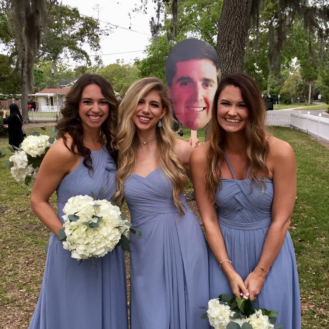 Three bridesmaids in dusty blue dresses holding white bouquets and posing outdoors.