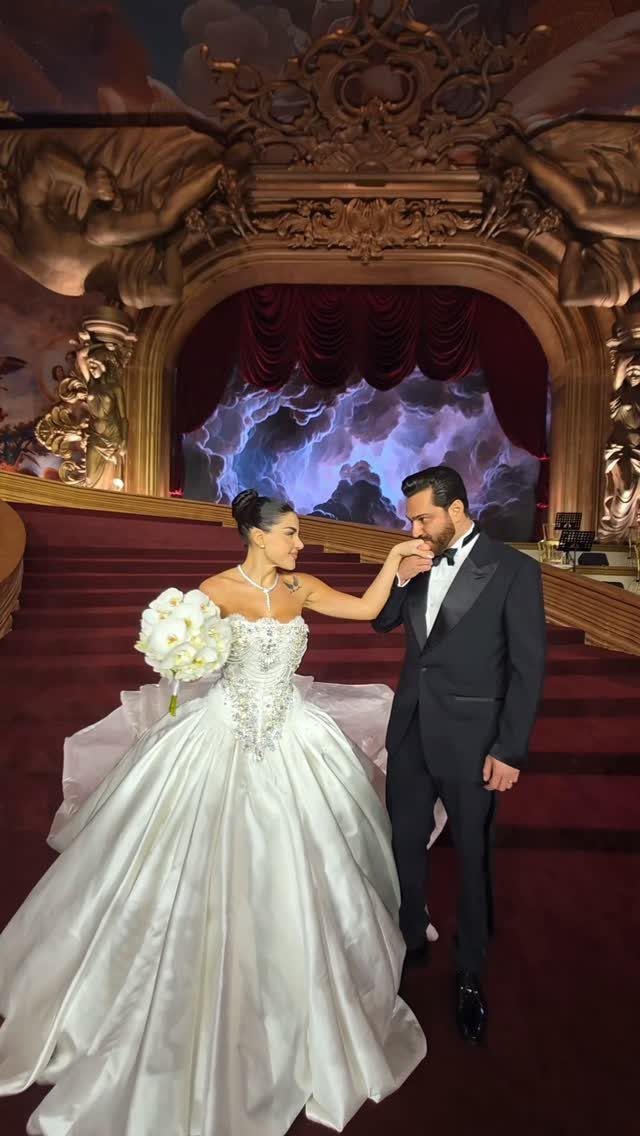 Bride in white ball gown and groom in tuxedo in ornate ballroom