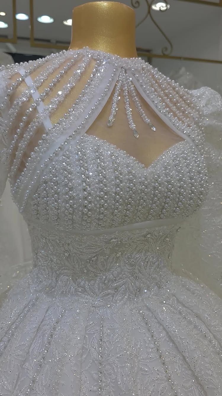 White beaded ballroom wedding gown with intricate pearl embroidery on a gold mannequin
