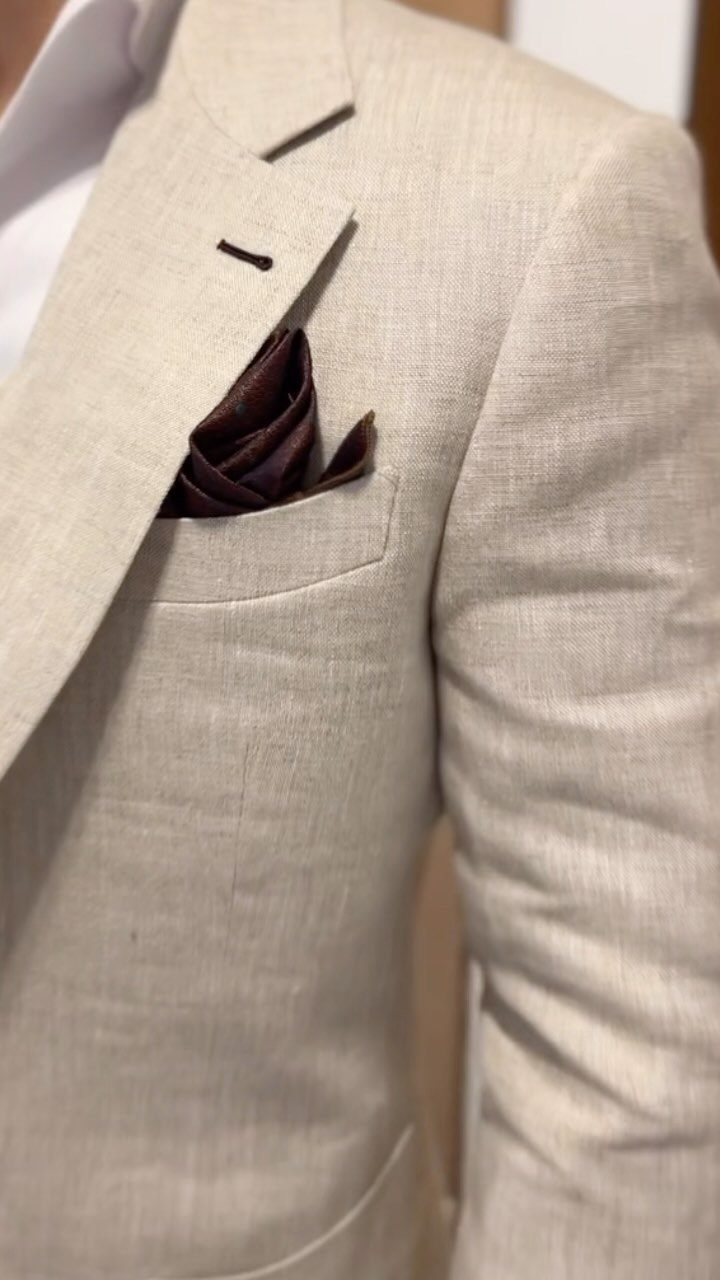 Light beige linen suit jacket with a dark brown pocket square and white shirt.