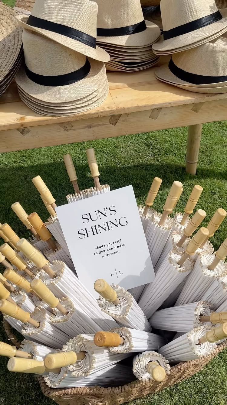 Straw hats and white parasols arranged on a table and in a basket.