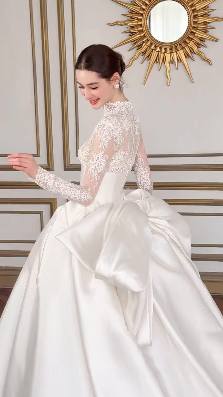 Woman in a white lace and satin ball gown wedding dress with large bow.