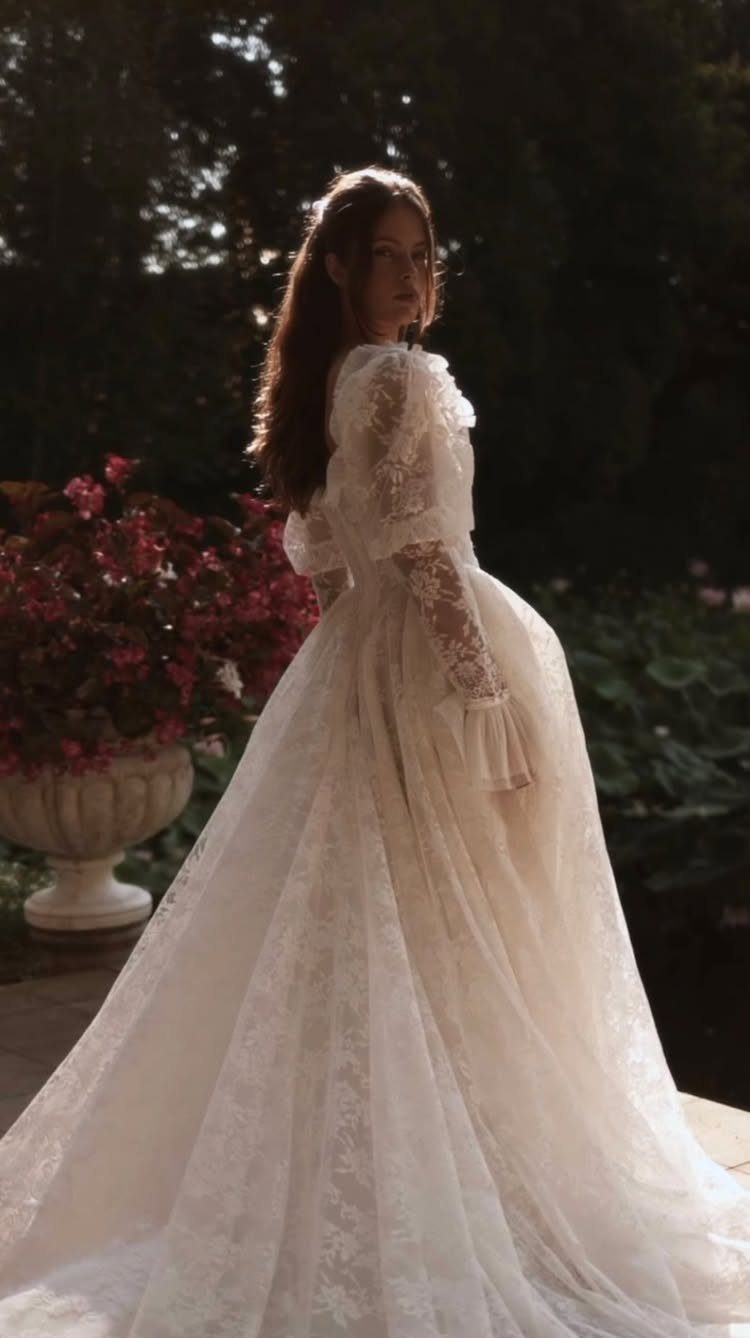 Woman in a white embroidered lace wedding gown standing in a garden