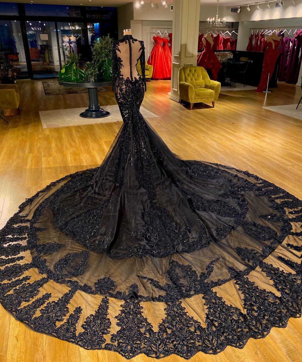 Black mermaid wedding dress with a long lace train on a mannequin.