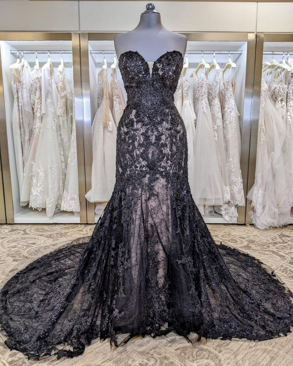 Strapless black lace wedding dress with a long train on a mannequin