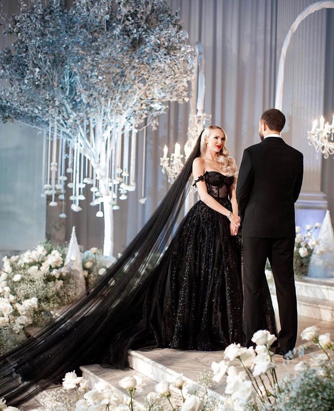 Woman in a sparkling black ballgown wedding dress and veil with a groom.