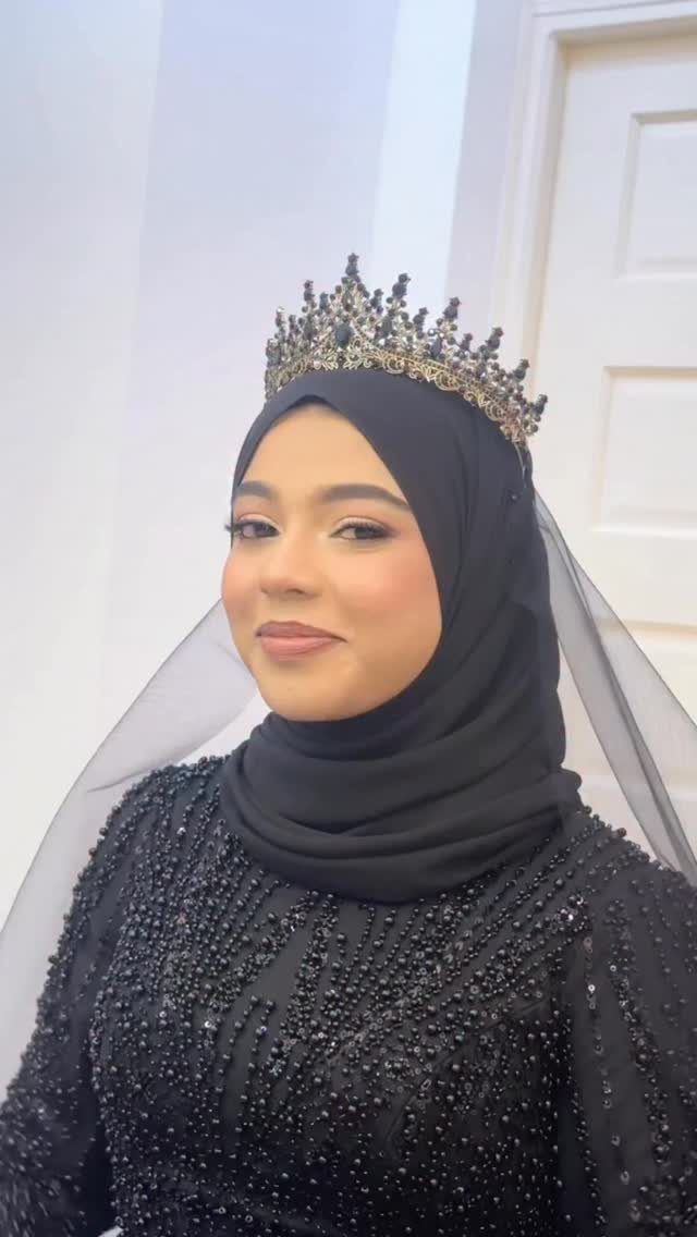 Woman in a black beaded wedding dress wearing a gold crown and hijab.