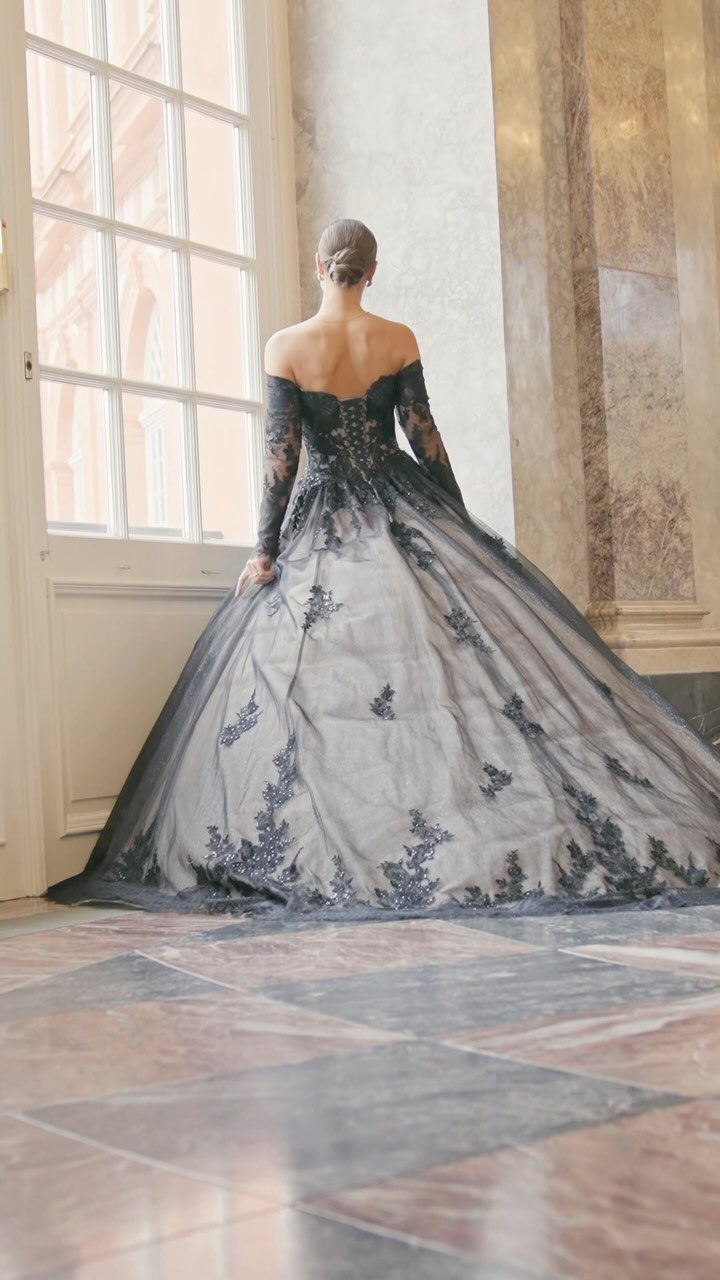 Woman from behind in a voluminous black lace wedding gown with long sleeves.