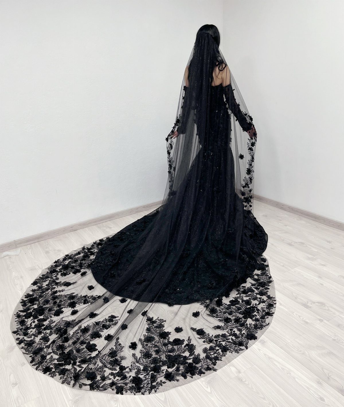 Long sleeve black wedding gown with a floral lace veil and train.