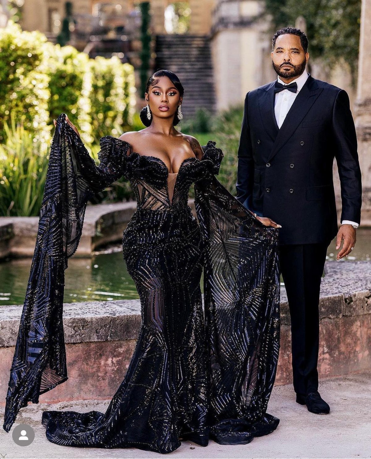 Woman in a shimmering black sequined wedding gown standing with a man in tuxedo.