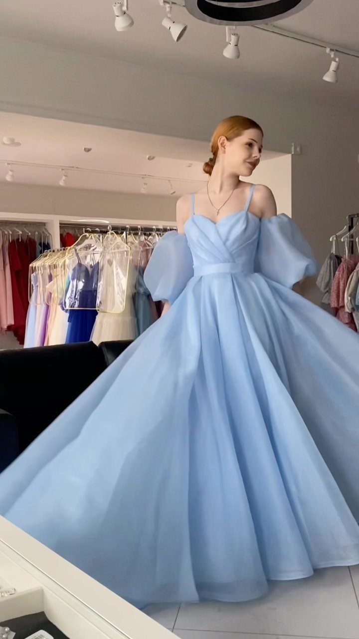 Woman wearing a voluminous ice blue tulle gown with off-the-shoulder puff sleeves.