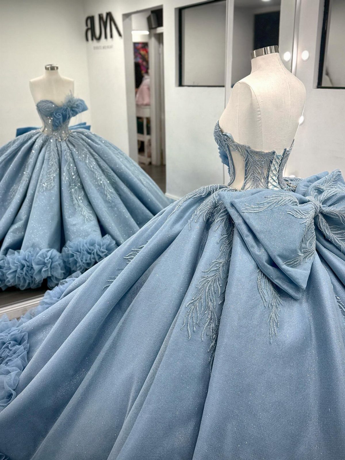 Light blue glittery ballgown with a large bow on a white mannequin
