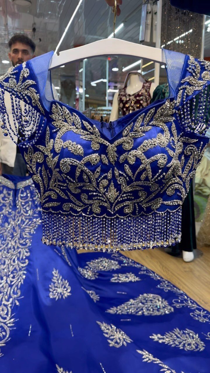 Royal blue bridal lehenga with silver embroidery and beaded fringe on a hanger