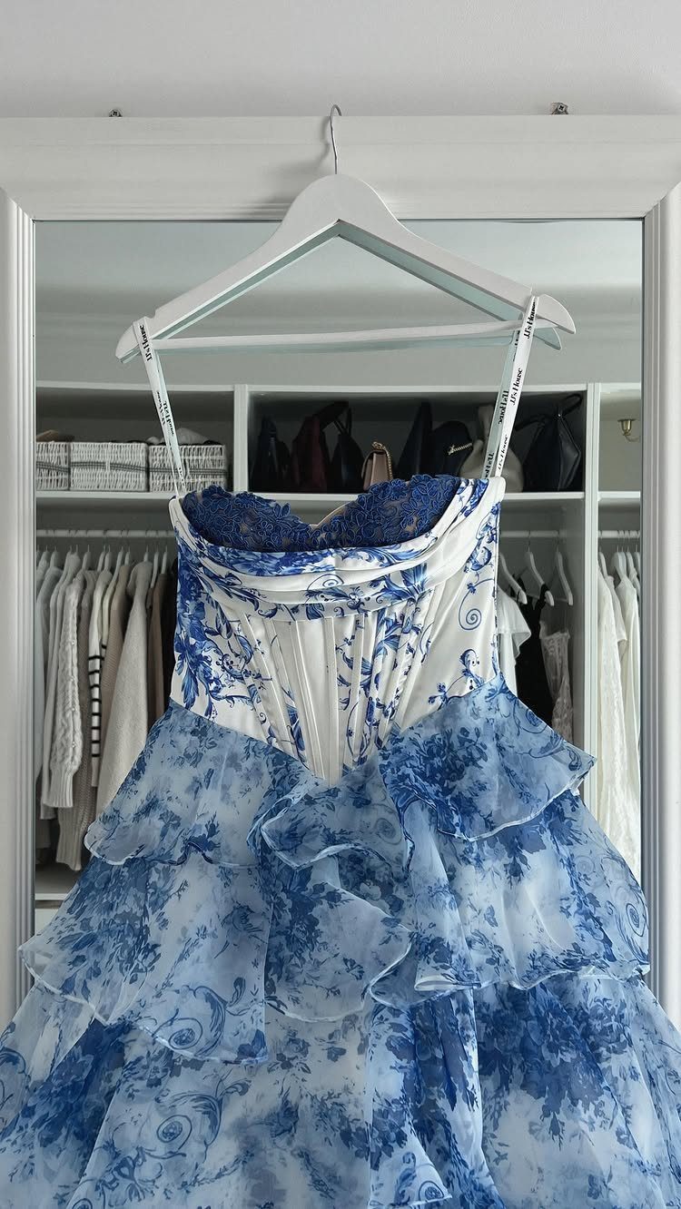 White and blue floral wedding dress with ruffled skirt hanging in a closet