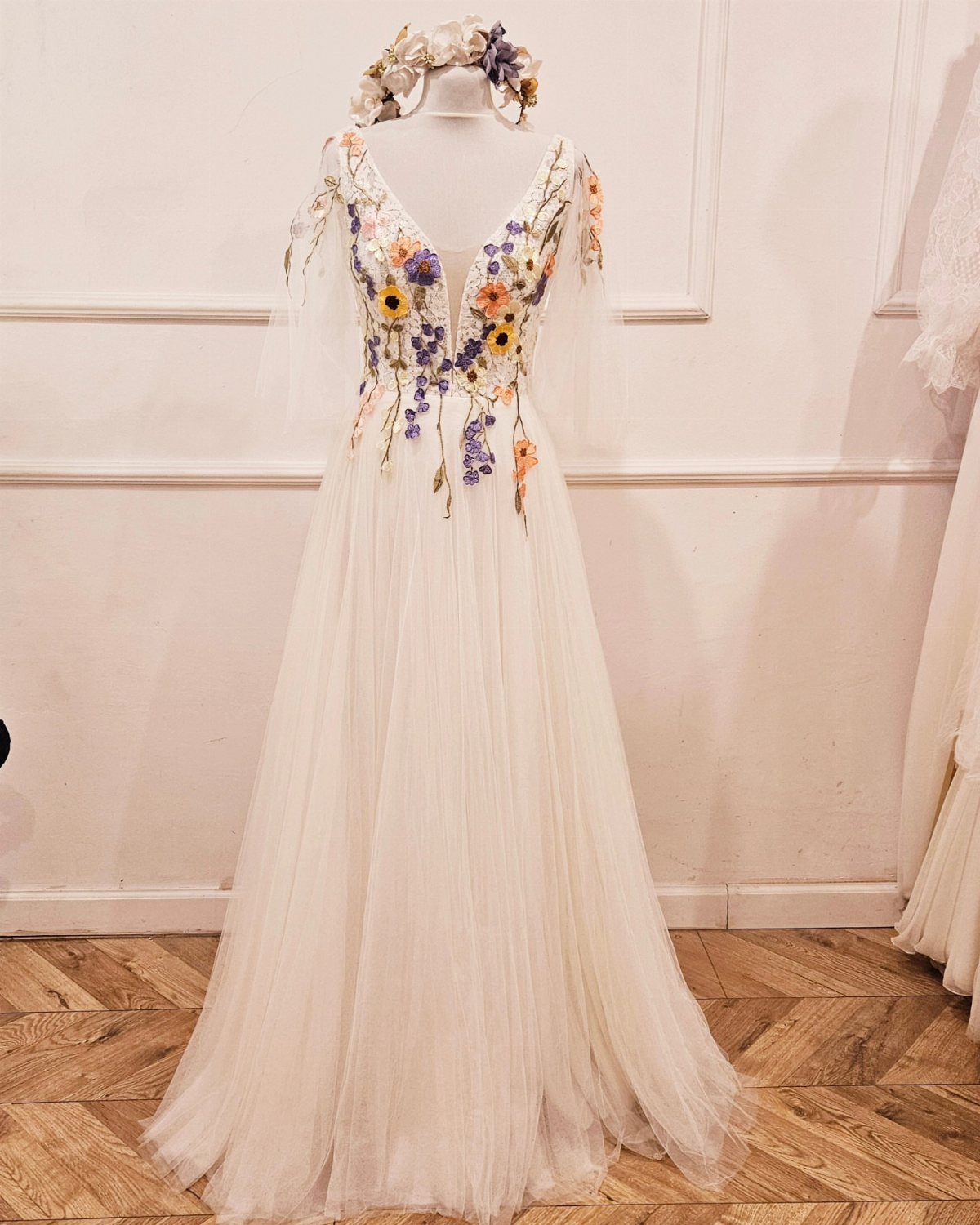 White bridal gown with colorful floral embroidery on the bodice and flowy tulle skirt.