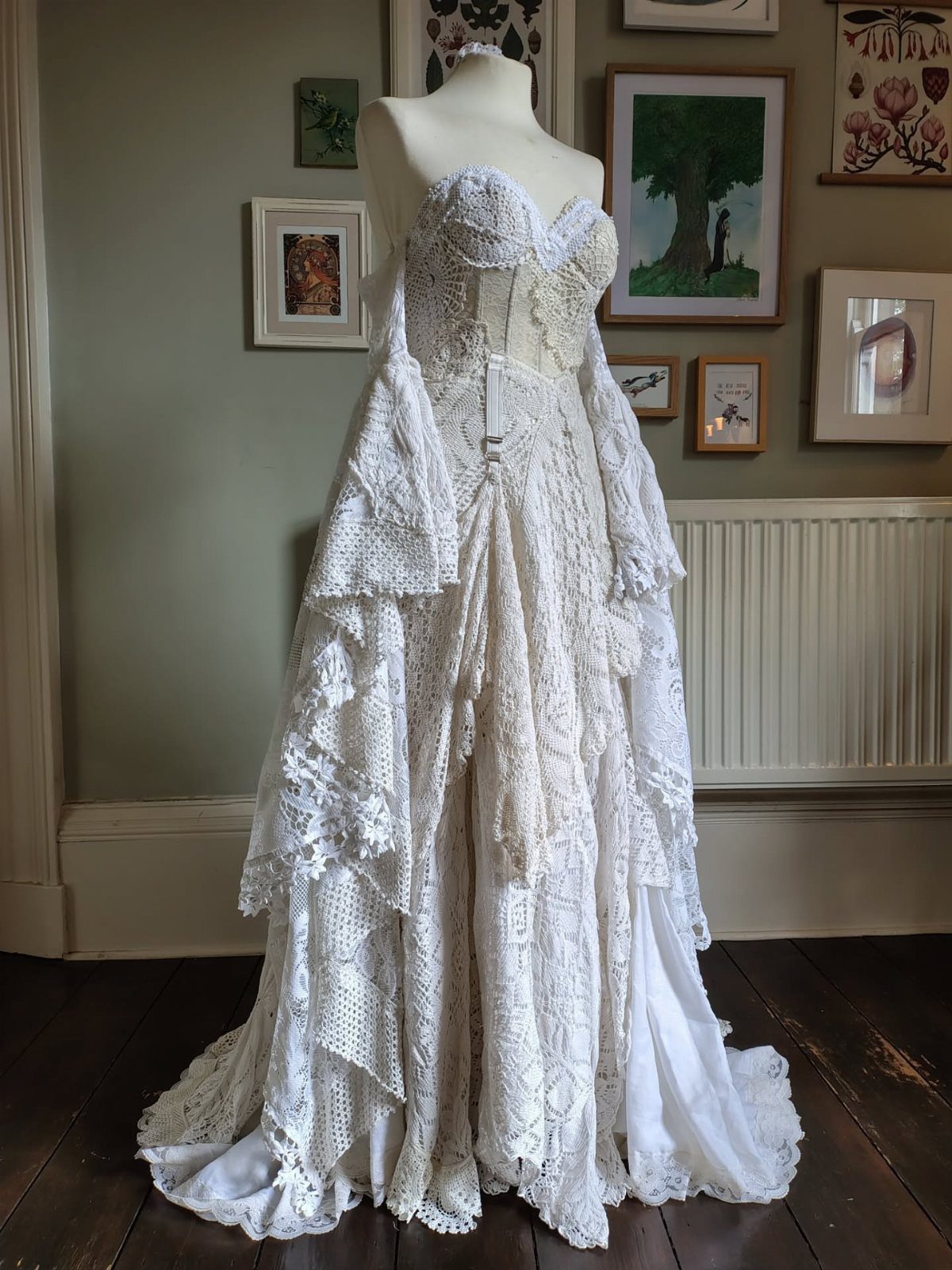 White boho wedding gown on a mannequin featuring intricate lace details and tiered skirts.