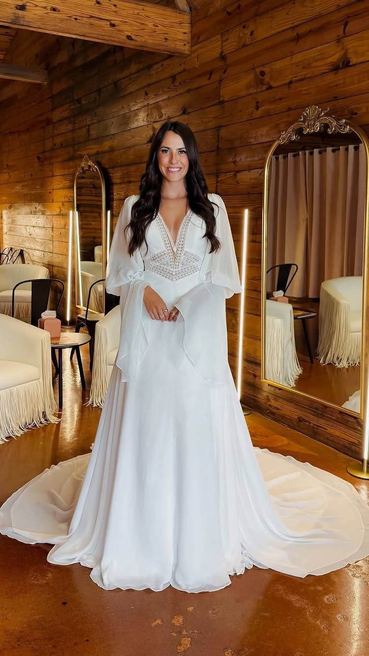 Woman in a white boho wedding dress with long flowing bell sleeves.