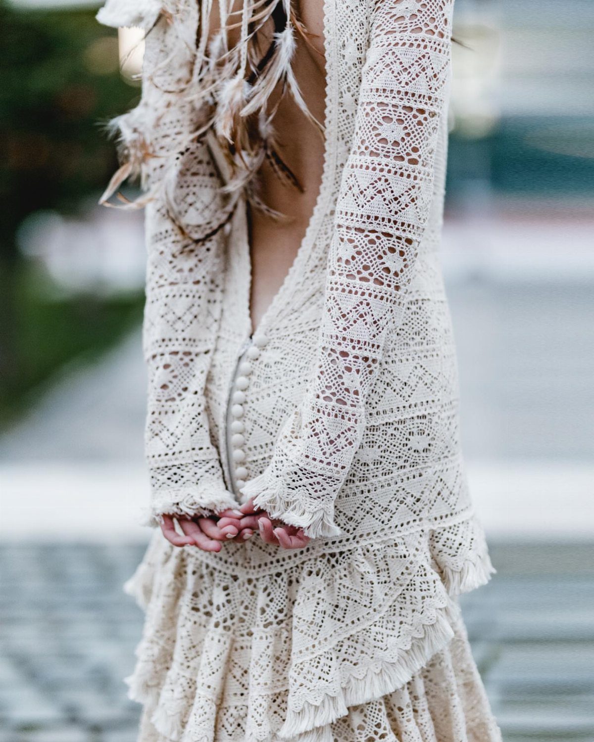 Cream lace wedding dress with open back and long sleeves seen from behind.