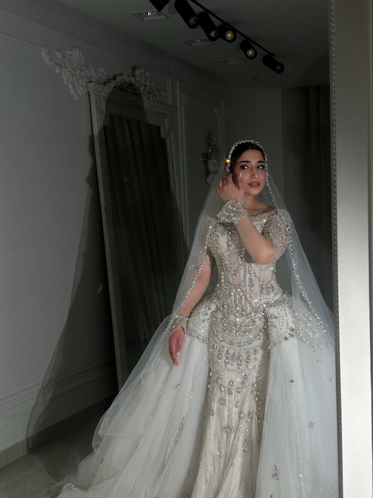 Woman in a beaded white mermaid bridal gown with a long sheer veil.