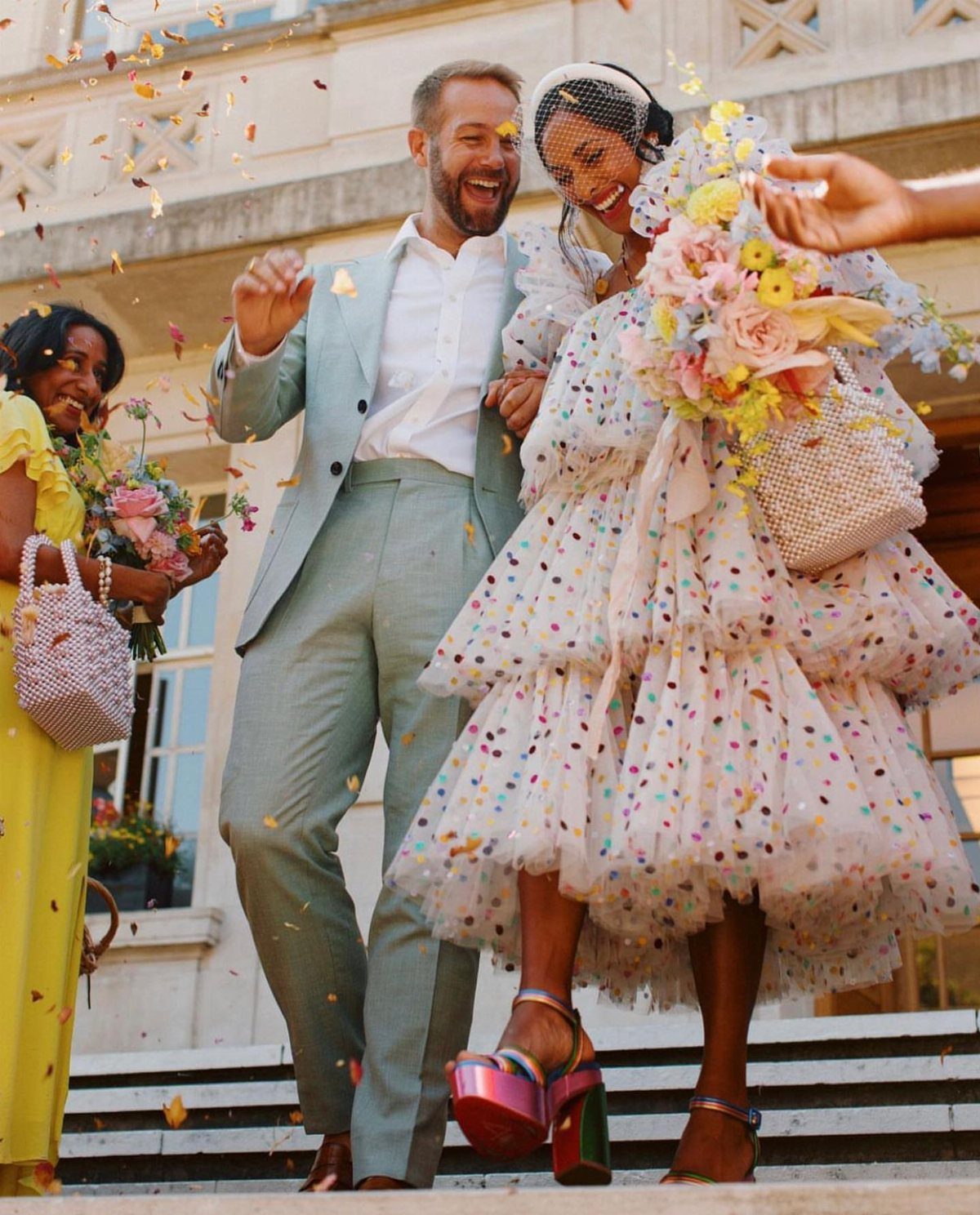 Couple celebrating wedding with bride wearing a colorful polka dot tiered short dress