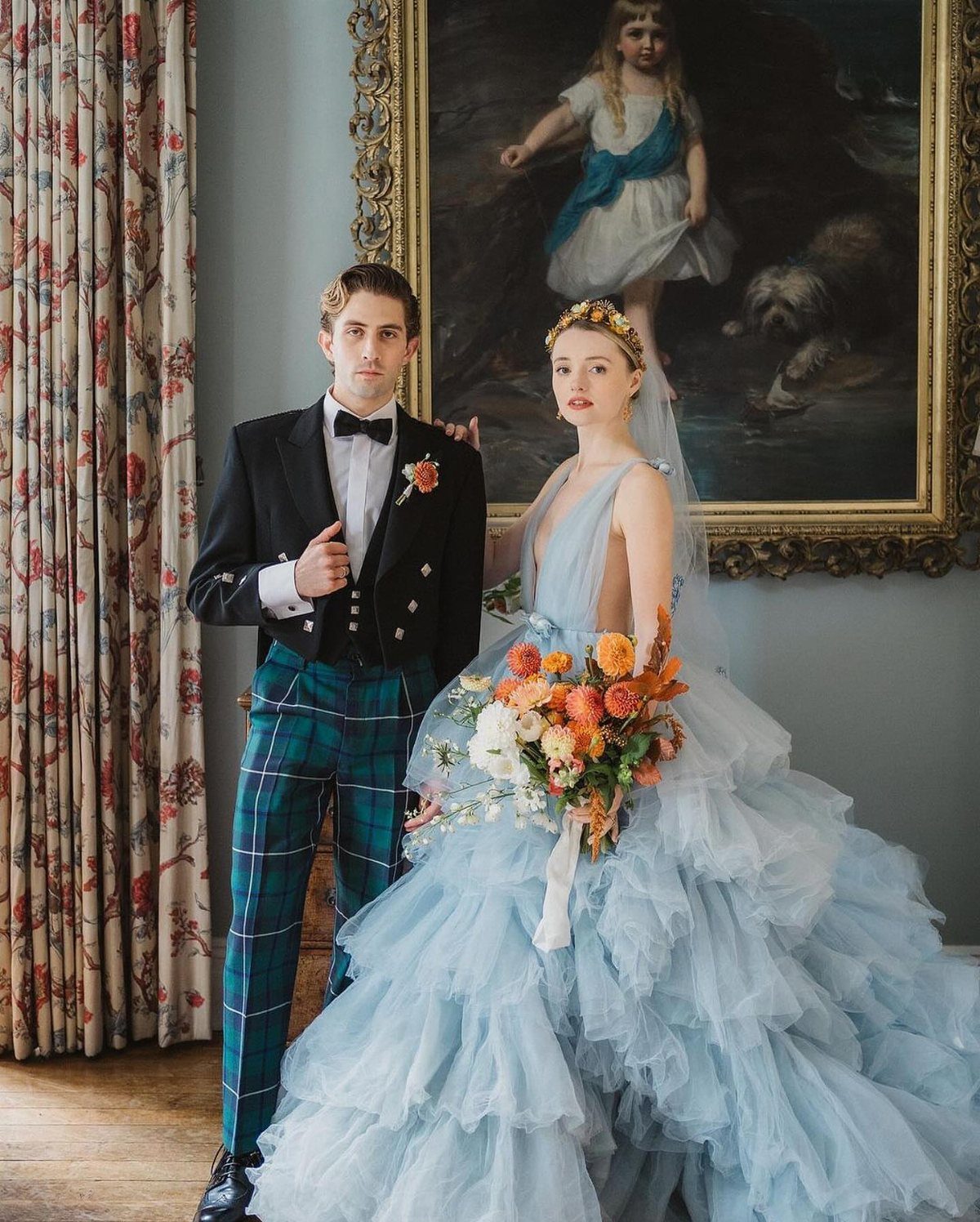 Couple in non-traditional wedding attire, woman in blue ruffled gown and man in plaid trousers.