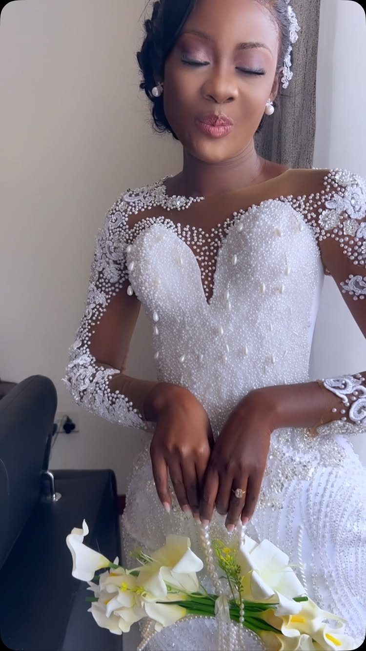Woman in a white beaded wedding gown holding a white calla lily bouquet.