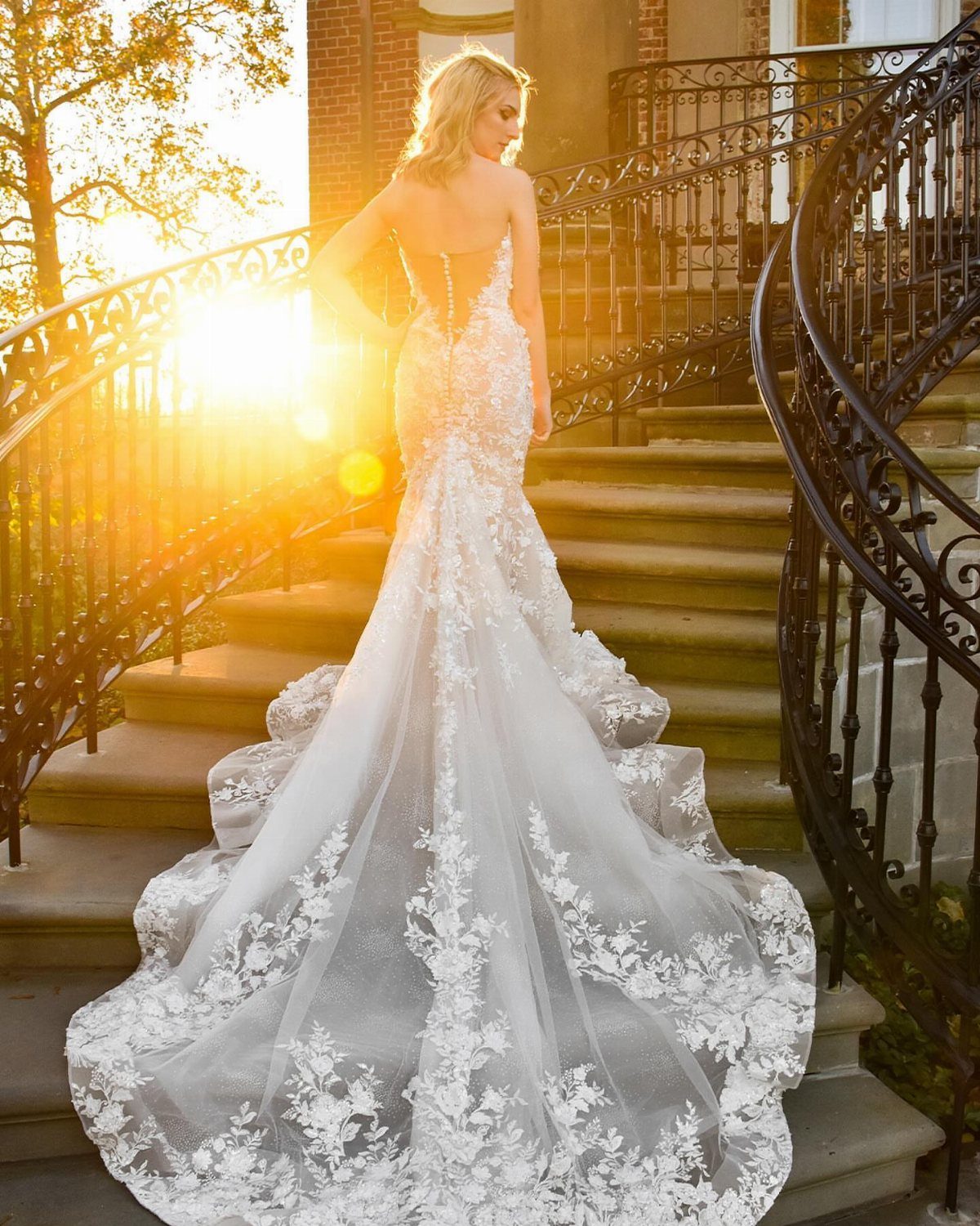 Woman in a white lace fit and flare wedding dress on stone stairs.
