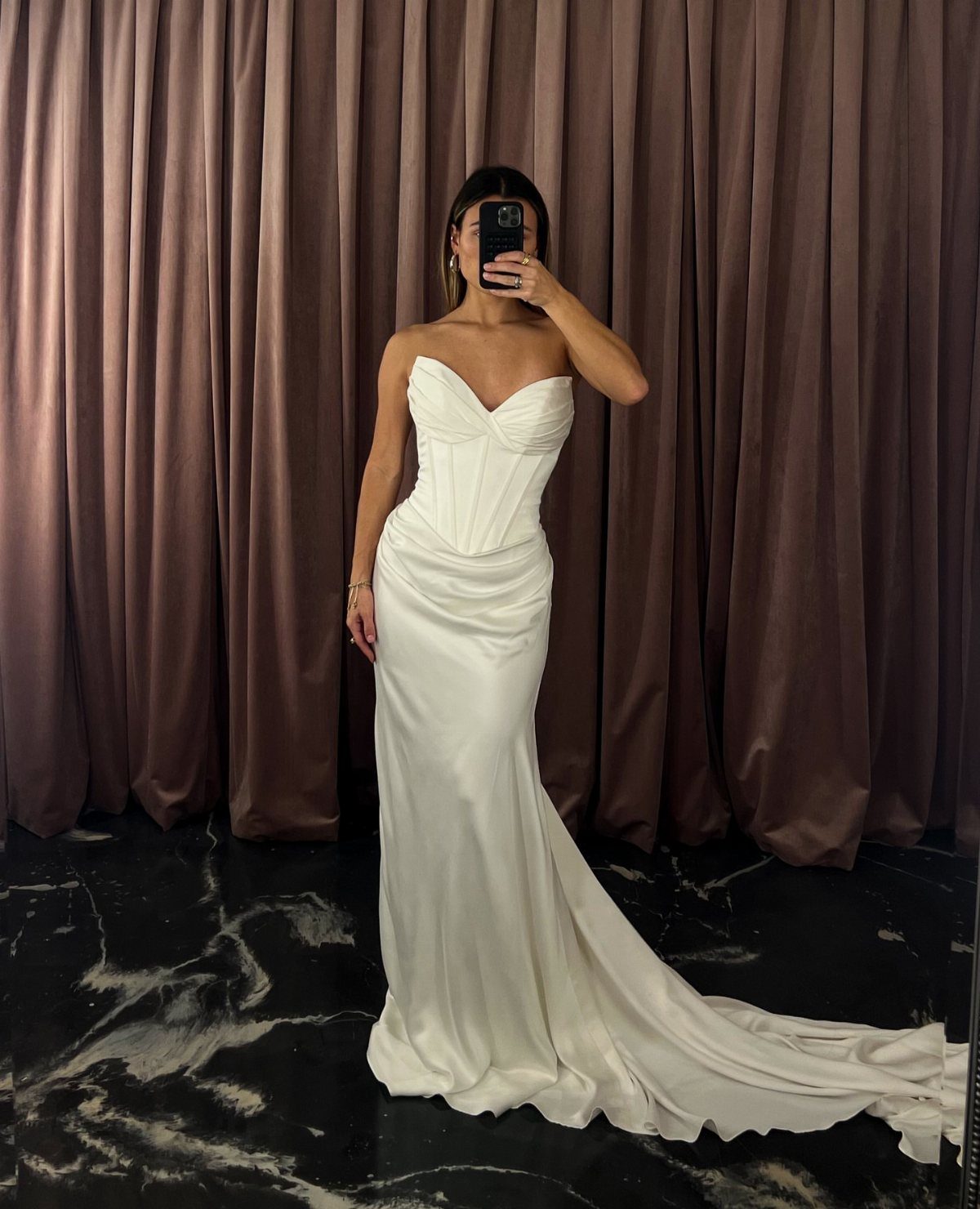 Woman in a strapless white satin wedding dress with a sweetheart neckline and train.