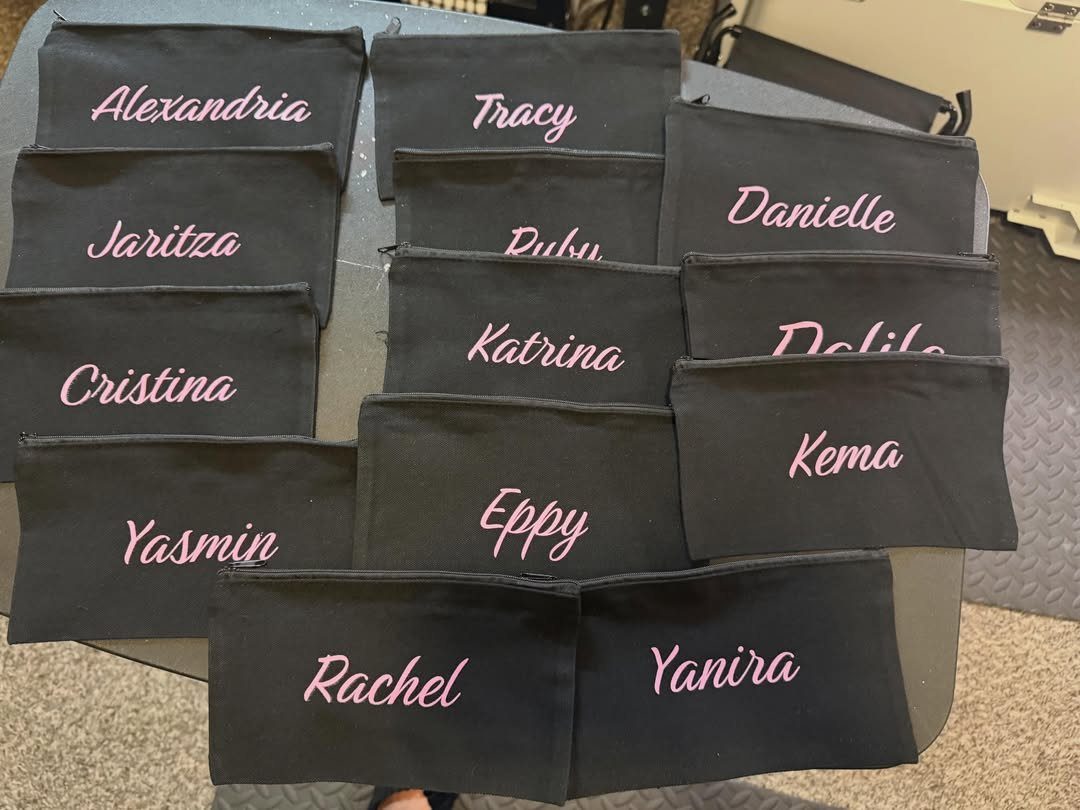 Black fabric makeup bags with personalized names printed in pink cursive script.