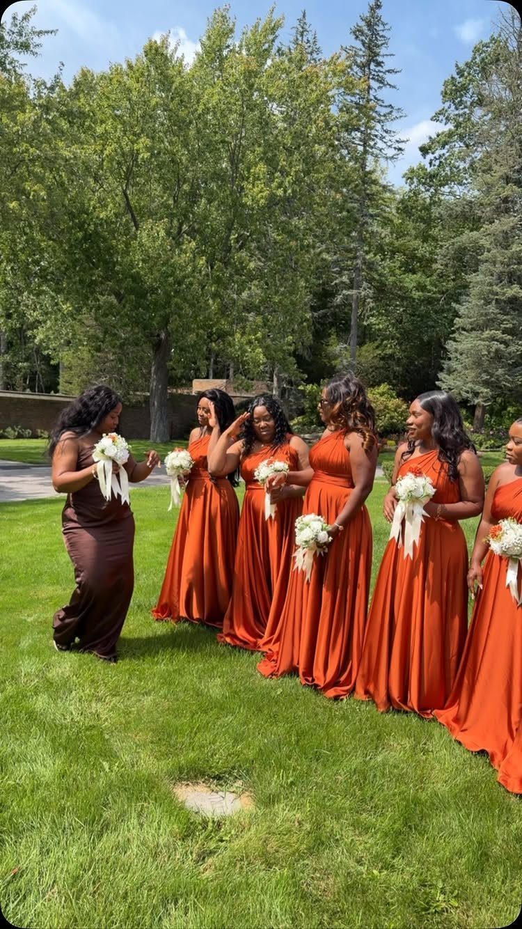 Six bridesmaids in burnt orange and dark brown dresses holding white floral bouquets.