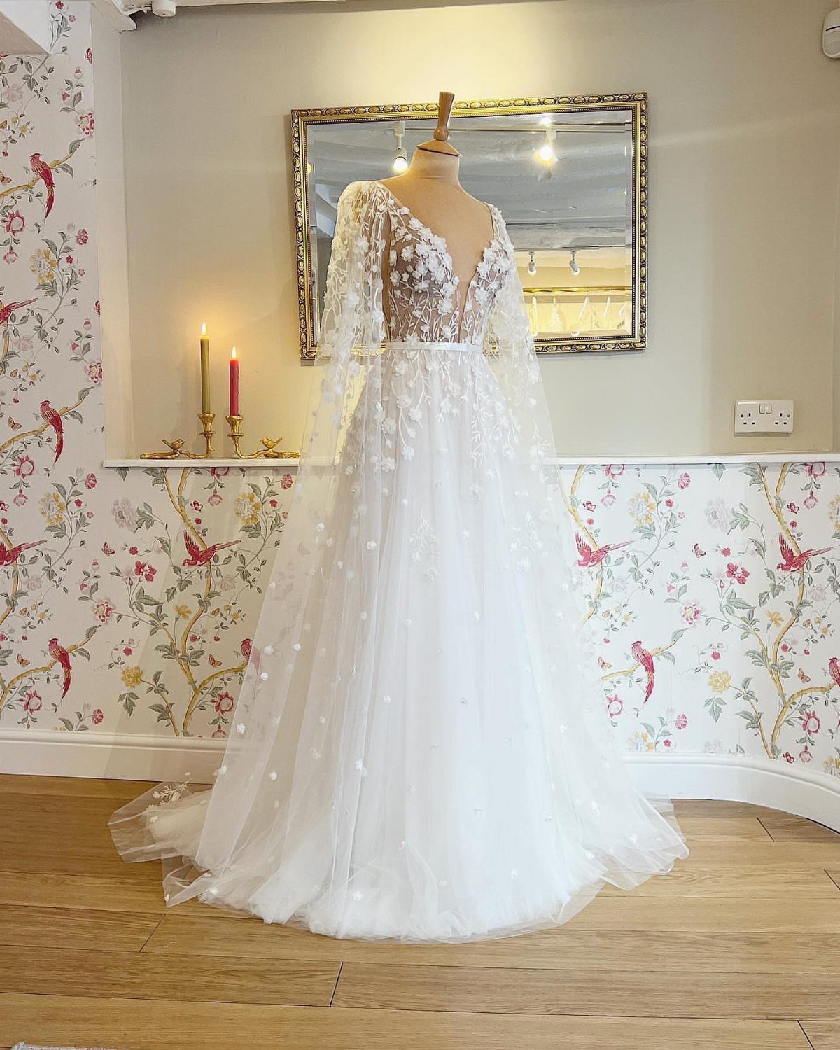 White wedding dress with 3D floral details and a long sheer cape