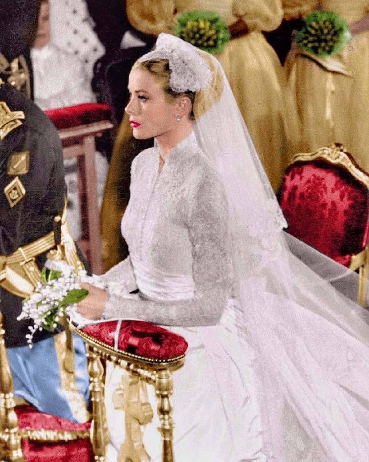 Woman in high-neck lace wedding dress with veil seated in ornate gold chair.