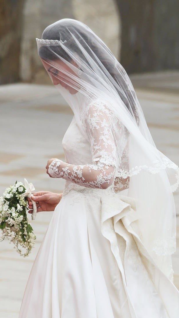 Woman in white wedding dress with lace sleeves, tiara, and sheer veil.